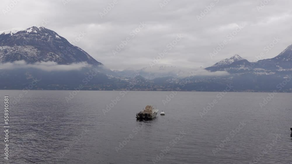 Varenna lake como, Italy vacation destination in cold snow winter calm and relax boat floating in lake scenery Varenna lake como, Italy vacation destination in cold snow winter calm and relax boat floating in lake scenery