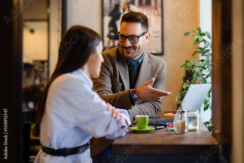 Two People Discussing Ideas and Working in Cafe