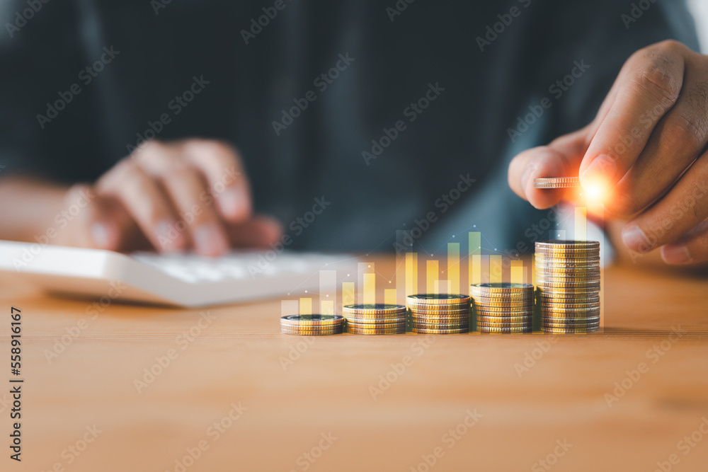 Increasing graph of a businessman's hand with money coins stacking, business investment profit, and deposit dividend saving growth concept Increasing graph of a businessman's hand with money coins stacking, business investment profit, and deposit dividend saving growth concept