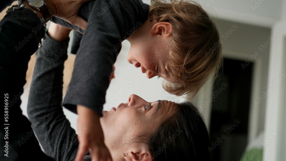 Fototapeta premium Toddler jumping in mother arms, parent lifting two year old baby in air