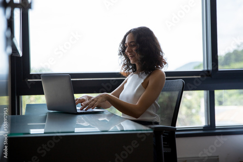 woman working on laptop, woman sitting in front of her computer, woman working from home office, student and her computer