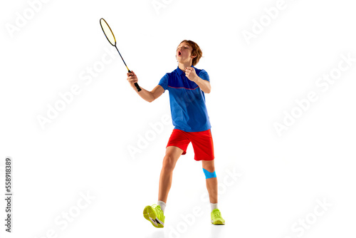 Portrait of teen boy in uniform, badminton player during game, training isolated over white background. Winning emotions