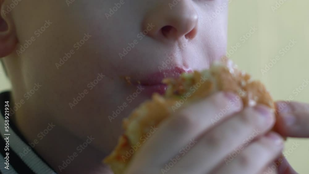 close-up caucasian boy 7-9 years old eats a cheeseburger, selective focus. a hungry child has breakfast with fast food. a boy in a cafe eats a burger. lips of a child eating close-up caucasian boy 7-9 years old eats a cheeseburger, selective focus. a hungry child has breakfast with fast food. a boy in a cafe eats a burger. lips of a child eating