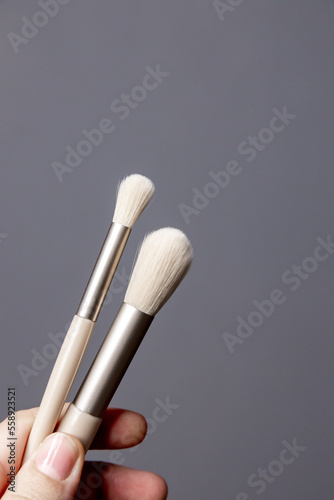 Makeup brushes in hand on a plain gray background isolated