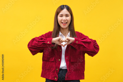 Women doing gesture heart shape with both hands and happiness smiling on isolated yellow background