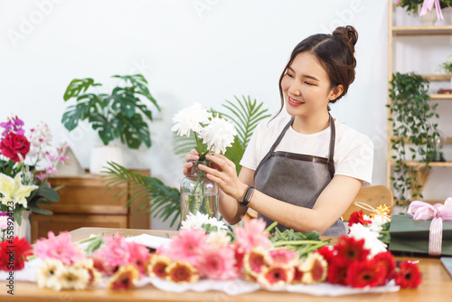 Florist concept, Female florist arrange white chrysanthemum in vase with happiness in flower shop