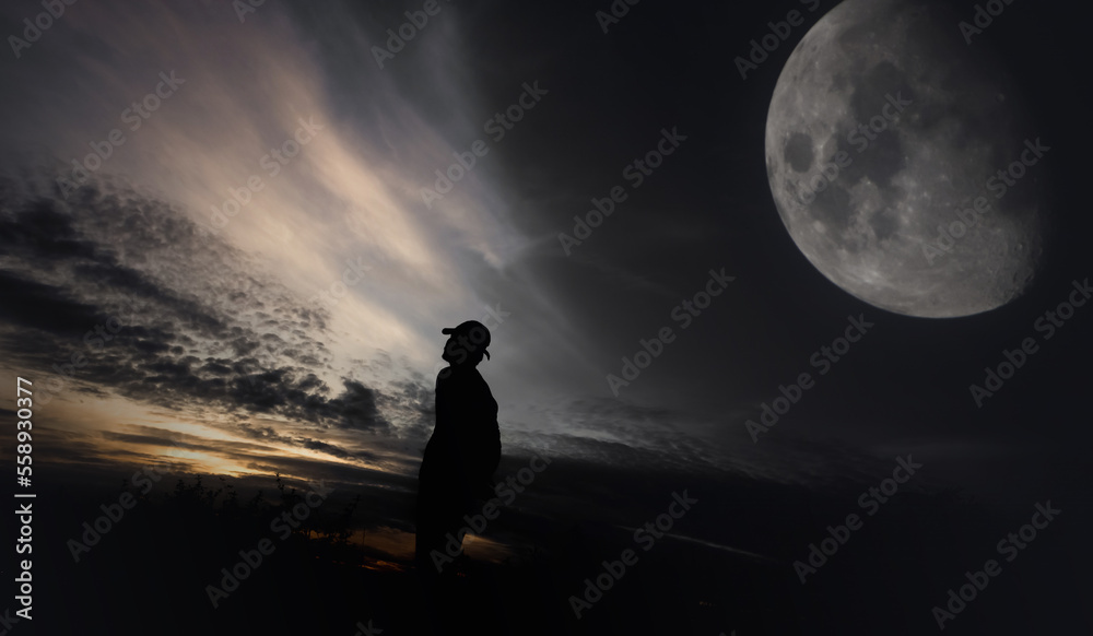 Man standing against moon in the background at night.