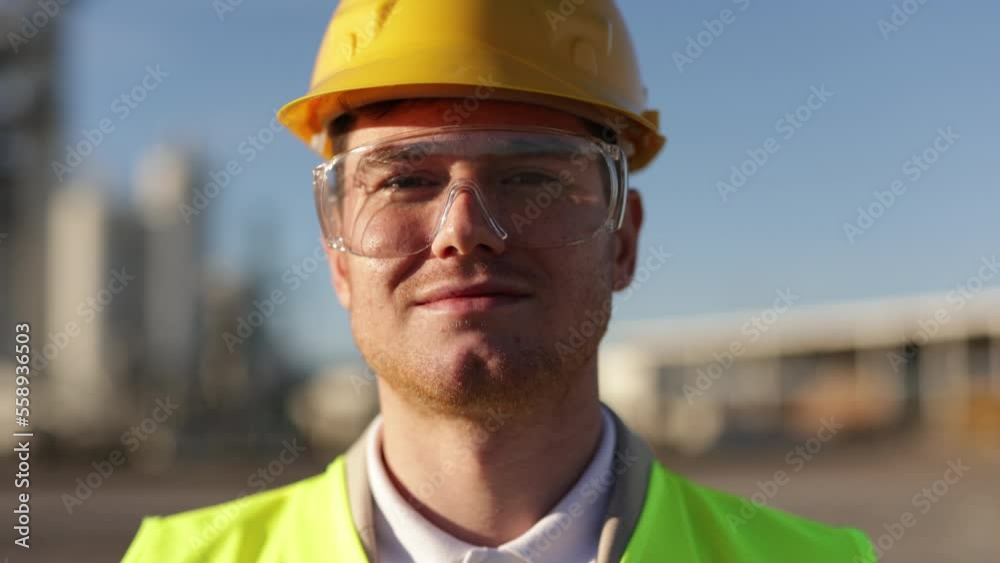 Portrait of Professional Heavy Industry Engineer, Worker Wearing Safety Uniform, Goggles and Hard Hat. In the Background Unfocused Large Industrial Factory Portrait of Professional Heavy Industry Engineer, Worker Wearing Safety Uniform, Goggles and Hard Hat. In the Background Unfocused Large Industrial Factory
