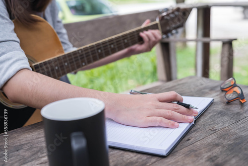 songwriter thinking and writing notes,lyrics in book at studio. playing live acoustic guitar.concept for musician creative.artist composer in work process.people relaxing time with instrument
Photo