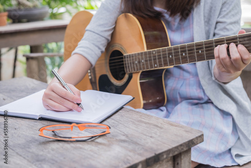 songwriter thinking and writing notes,lyrics in book at studio. playing live acoustic guitar.concept for musician creative.artist composer in work process.people relaxing time with instrument
Photo