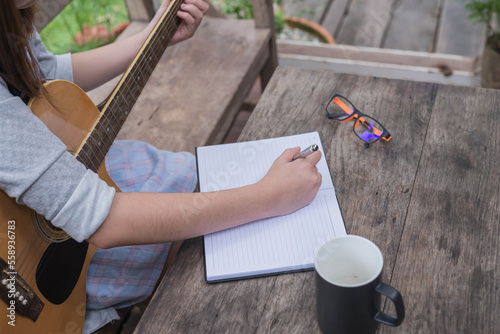 songwriter thinking and writing notes,lyrics in book at studio. playing live acoustic guitar.concept for musician creative.artist composer in work process.people relaxing time with instrument
Photo