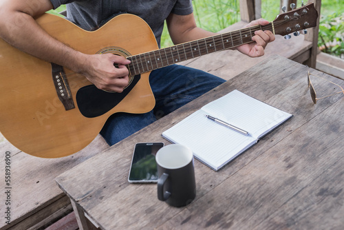 songwriter thinking and writing notes,lyrics in book at studio.man playing live acoustic guitar.concept for musician creative.artist composer in work process.people relaxing time with instrument
Photo
