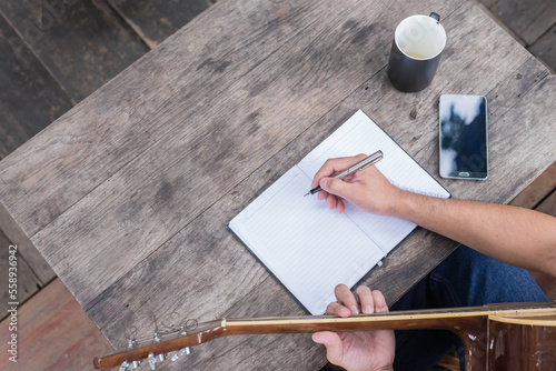 songwriter thinking and writing notes,lyrics in book at studio.man playing live acoustic guitar.concept for musician creative.artist composer in work process.people relaxing time with instrument
Photo