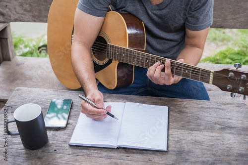 songwriter thinking and writing notes,lyrics in book at studio.man playing live acoustic guitar.concept for musician creative.artist composer in work process.people relaxing time with instrument
Photo