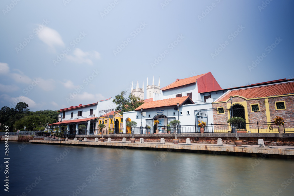 Malacca, Malaysia - August 10, 2022: Along the Melaka river with the old brightly painted houses. Bars and restaurants line the course of the river. Long Exposure capture smooths silky water.
