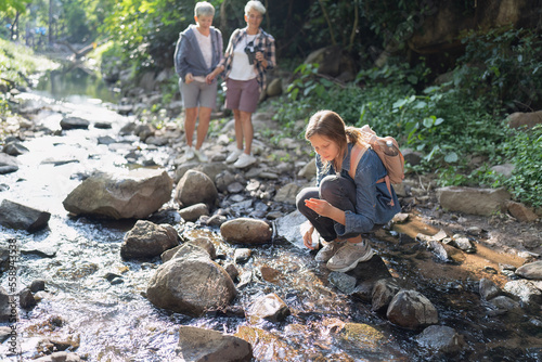Backpack tourist travel hiking outdoor adventure walking in row on rock side of water stream flow