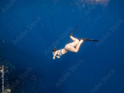 A beautiful girl swims underwater. Girl in swimsuit. Blue water. Coral reef. Diver girl.