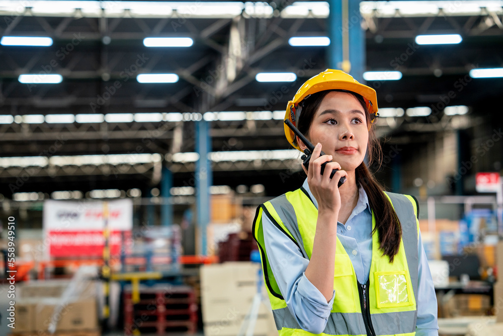 custom made wallpaper toronto digital Asian female workers wearing reflective jackets and safety helmets use walkie-talkies inside a warehouse to deliver supplies.Factory and logistics concept