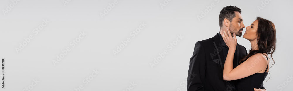 side view of bearded man and brunette woman looking at each other isolated on grey, banner. side view of bearded man and brunette woman looking at each other isolated on grey, banner.