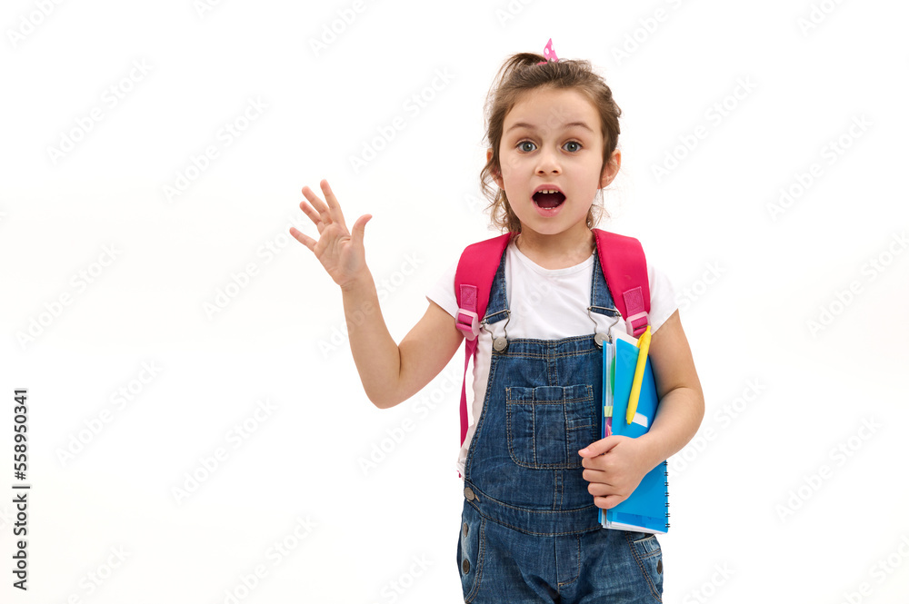 Surprised Caucasian little child girl, primary school student expressing surprise, posing with school supplies over white background. Copy space for your advertising text. Education Knowledge Learning Surprised Caucasian little child girl, primary school student expressing surprise, posing with school supplies over white background. Copy space for your advertising text. Education Knowledge Learning