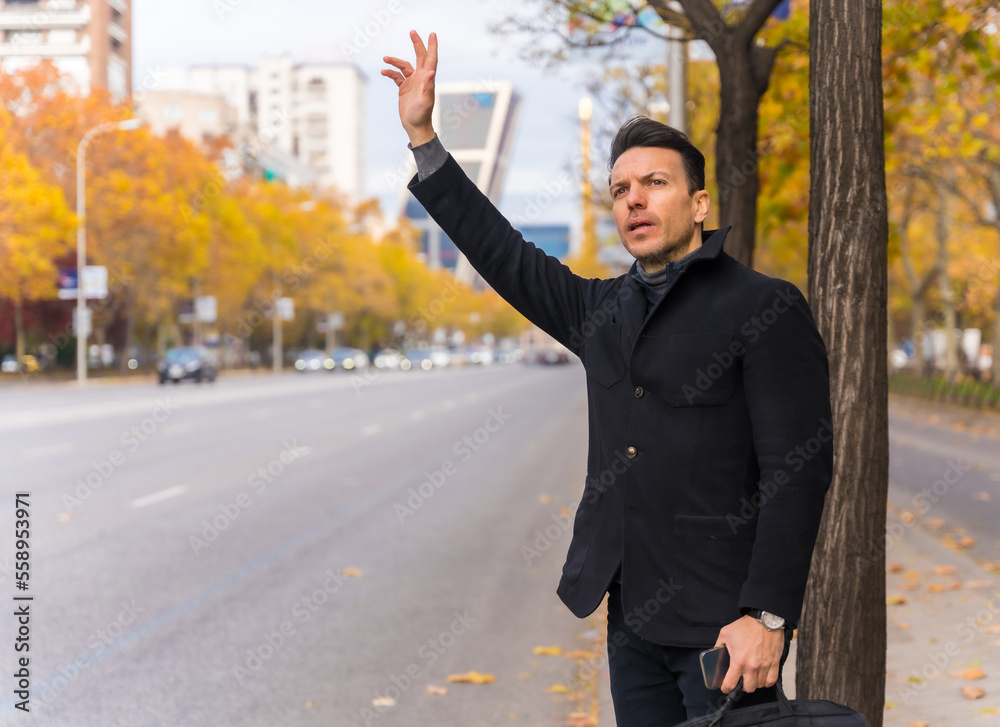 Middle-aged caucasian businessman hailing a taxi raising his hand to go to work Middle-aged caucasian businessman hailing a taxi raising his hand to go to work