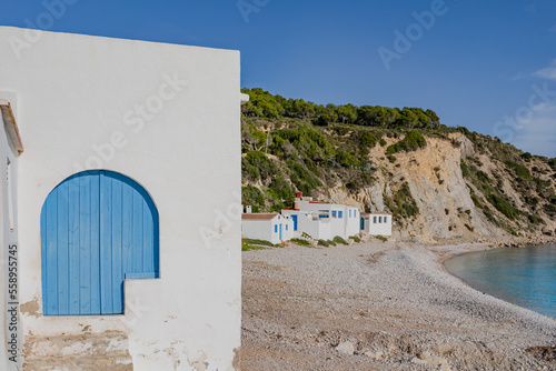White houses with blue doors. Portitxol beach, Cala Barraca in the Autonomous Community of Valencia, Alicante, Spain. White stone beach. photo