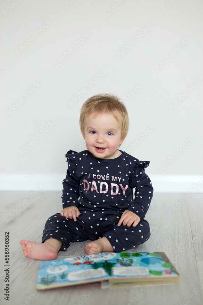 Happy smiling caucasian baby girl with lights garland sitting on the floor photo Happy smiling caucasian baby girl with lights garland sitting on the floor photo