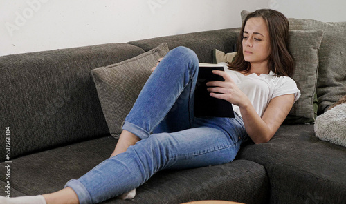 Free Download Young woman relaxes in the living room while reading a book - home shooting - GFXLoad