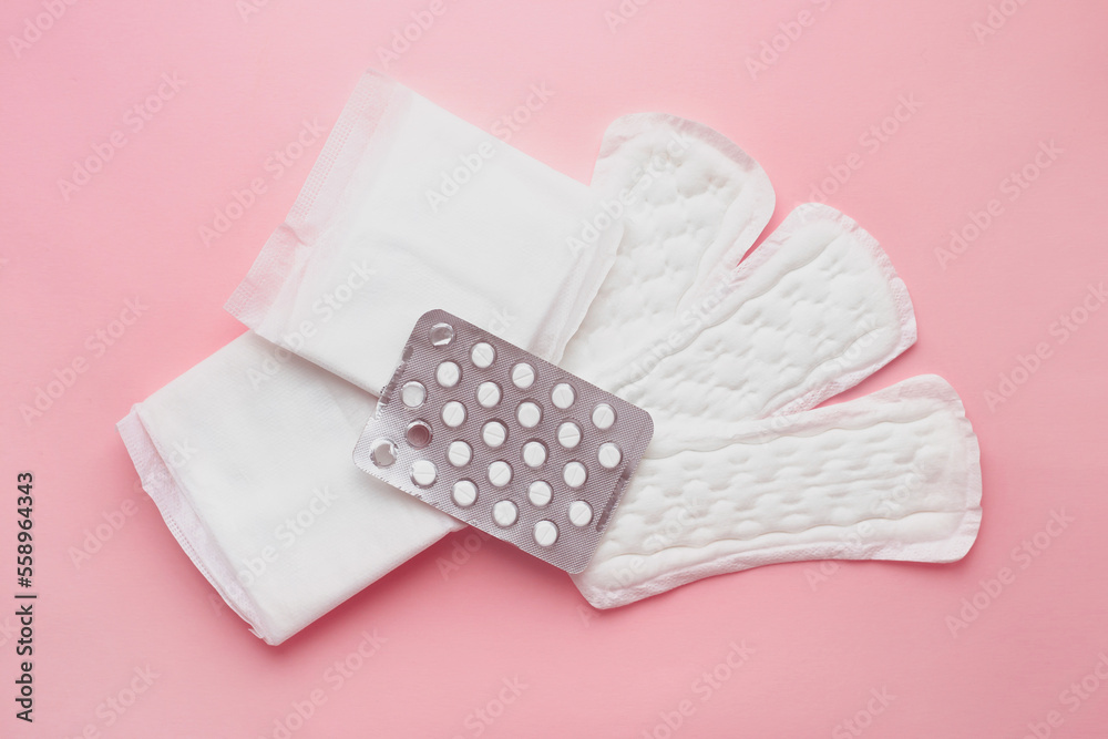 Different types of female pads and contraceptive tablets during the menstrual cycle on a pink background