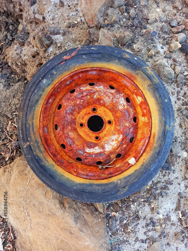 Close up of rusty and painted old wheel. Rusty bright colored rim. Aerial view of wheel plate.