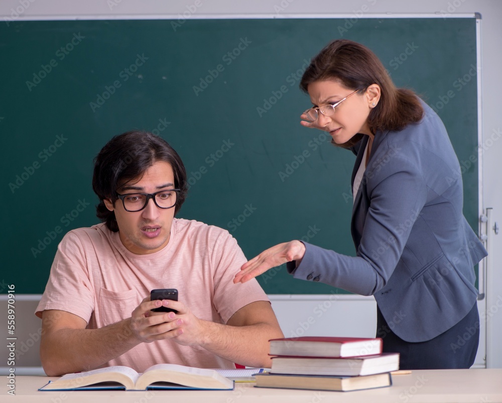 Old female teacher and male student in the classroom Old female teacher and male student in the classroom