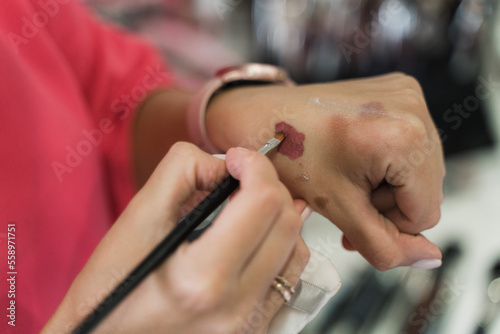 make-up artist selects the color on his hand with a brush