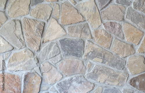 Abstract rock stone wall inside. Straight wall background texture. Irregular and random stone pattern. Large rock pattern texture with many hues of grey, yellow, red and blue. Selective focus.