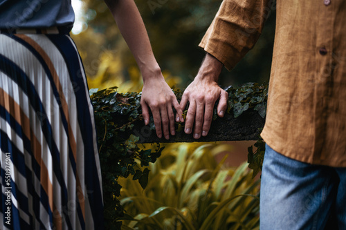 A romantic photo of a young couple's hands in a beautiful autumn park, shown in close-up as they rest close to each other on a reel