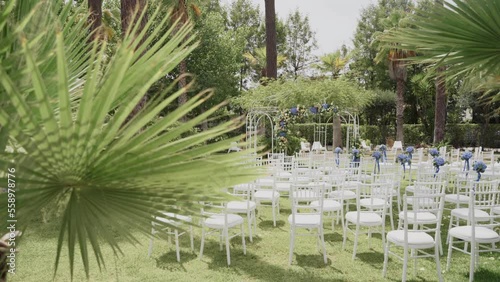 Wedding ceremony chairs and arch in the foreground of palm