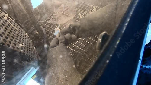 Shot blasting. Shot blasting of model printed on 3D printer from polyamide powder. A worker in sealed rubber gloves cleans the object by shot blasting in a shot blasting chamber. Industrial machine photo