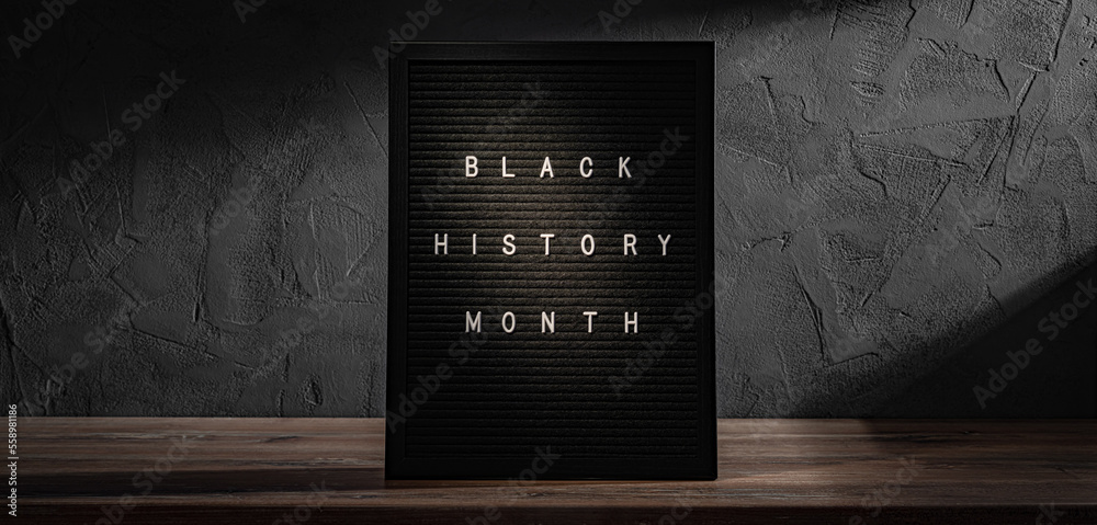 Black History Month words in frame on wooden shelf on black stone wall background