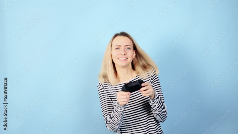 Excited cute young woman with joystick controller playing video games on blue background alone Happy blond female have fun relax after hard work day isolated Game addiction concept Excited cute young woman with joystick controller playing video games on blue background alone Happy blond female have fun relax after hard work day isolated Game addiction concept