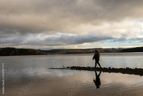Silhouette of woman by lake © Emilia