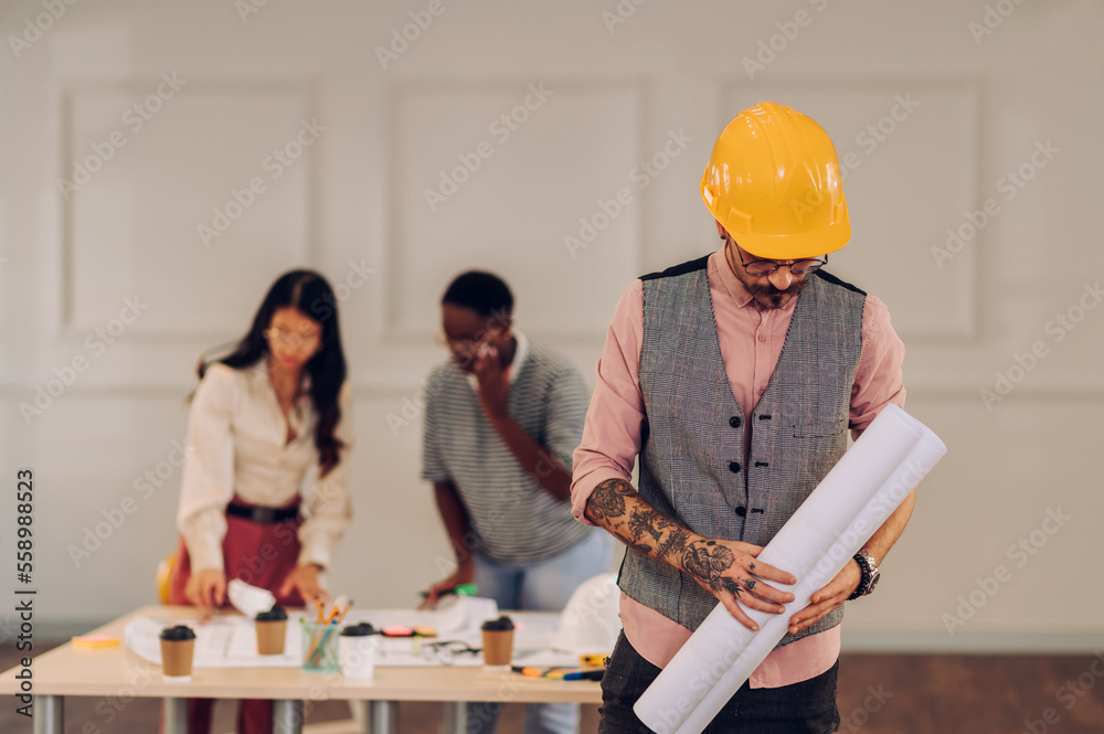 Male architect using blueprint and tablet in an office during a meeting Male architect using blueprint and tablet in an office during a meeting