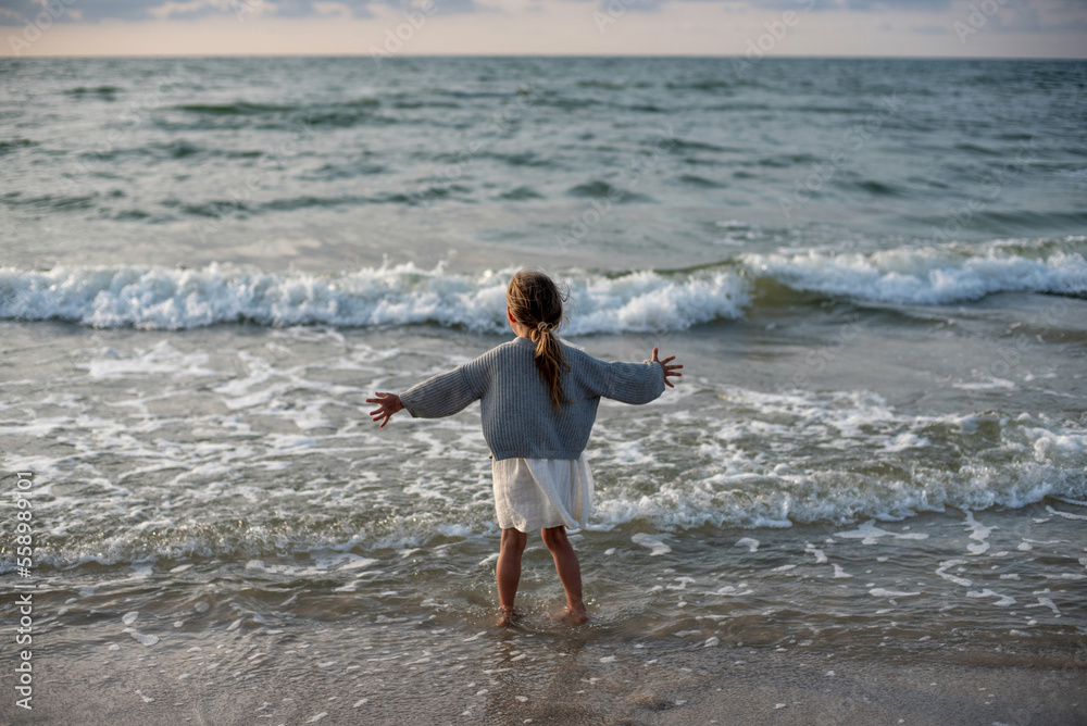 Child on the beach trying to embrace the sea 