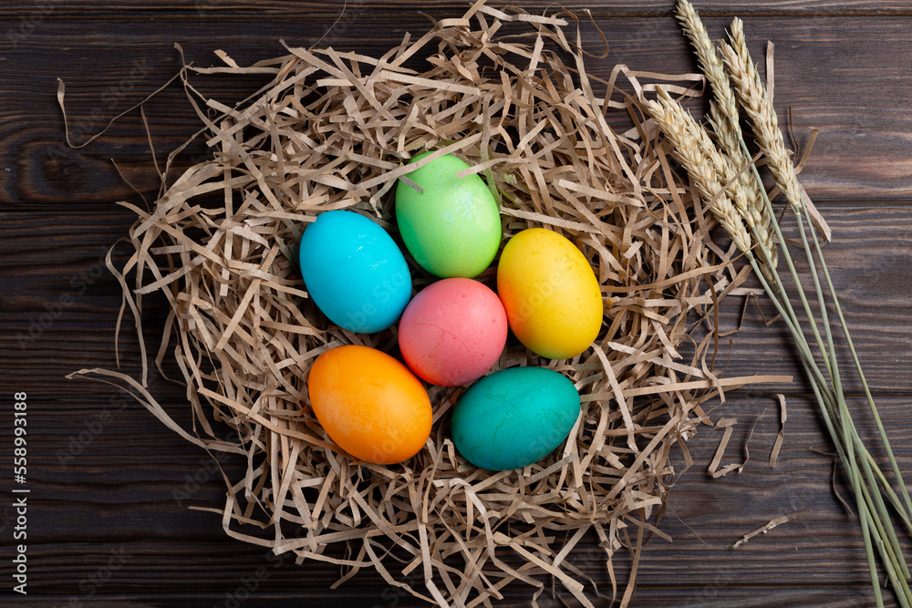 Painted multicolored eggs in a nest made of paper on a wooden background Painted multicolored eggs in a nest made of paper on a wooden background