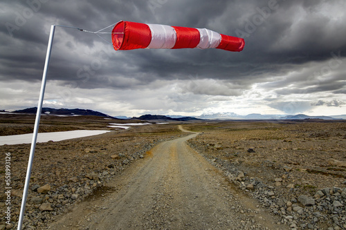 Striped Windbag and Mountain Gravel Road with dark clouds, Kaldidalur, Iceland. Concept for creative business ideas.