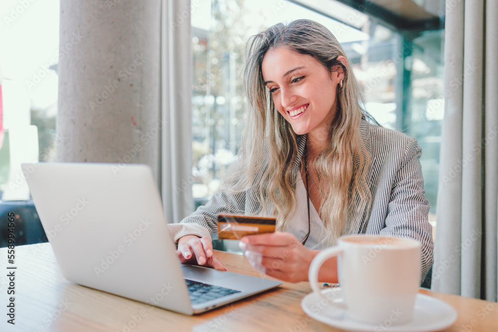 Happy young woman using credit card to buy online in a cafe. Online shopping addiction Happy young woman using credit card to buy online in a cafe. Online shopping addiction