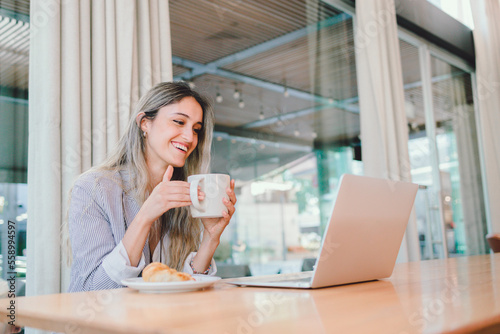 Young woman having a good time, using her laptop, drinking coffee from a mug. Habits to fight depression 