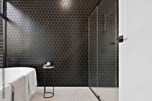 modern interior of bathroom with  shower, bath and hexagon black tiles