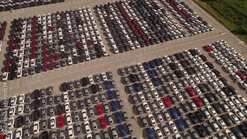  Aerial view of car storage or parking lot new unsold EV cars. Vehicle automaker and manufacturer parking facility. Low carbon footprint EV electric cars.
