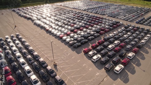 Aerial view of car storage or parking lot new unsold EV cars. Vehicle automaker and manufacturer parking facility. Low carbon footprint EV electric cars.