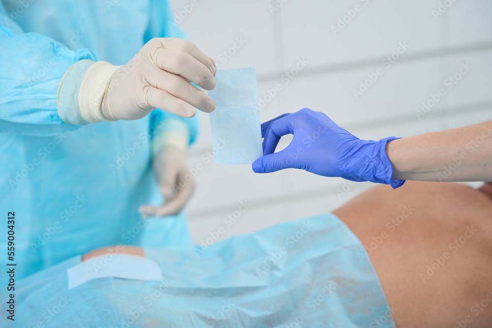 Fototapeta premium Assistant gives the surgeon plaster, they work in sterile condition