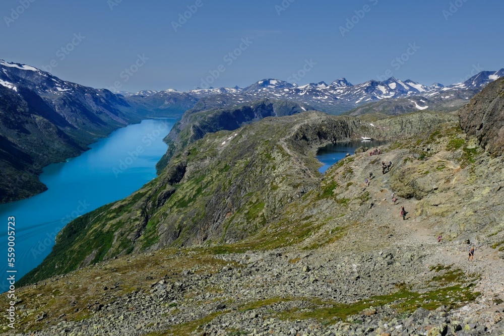 Scenic Besseggen trail in Jotunheimen, Norway - the most beautiful trekking trail in Norway. Silhouettes of hiking tourists on trail.